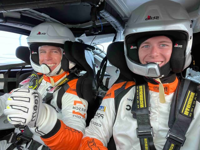 Two racing drivers in cockpit wearing helmets