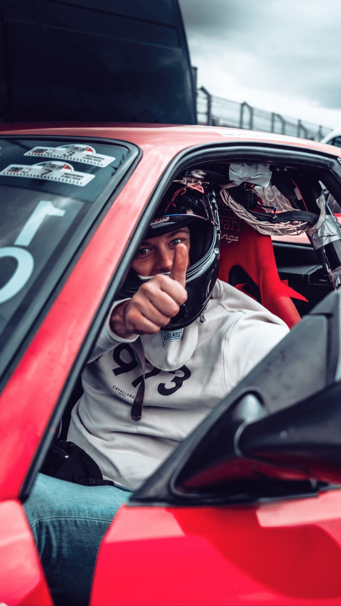 Racing driver giving thumbs up in cockpit