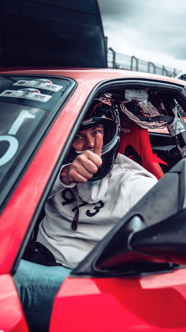 Racing driver giving thumbs up in cockpit
